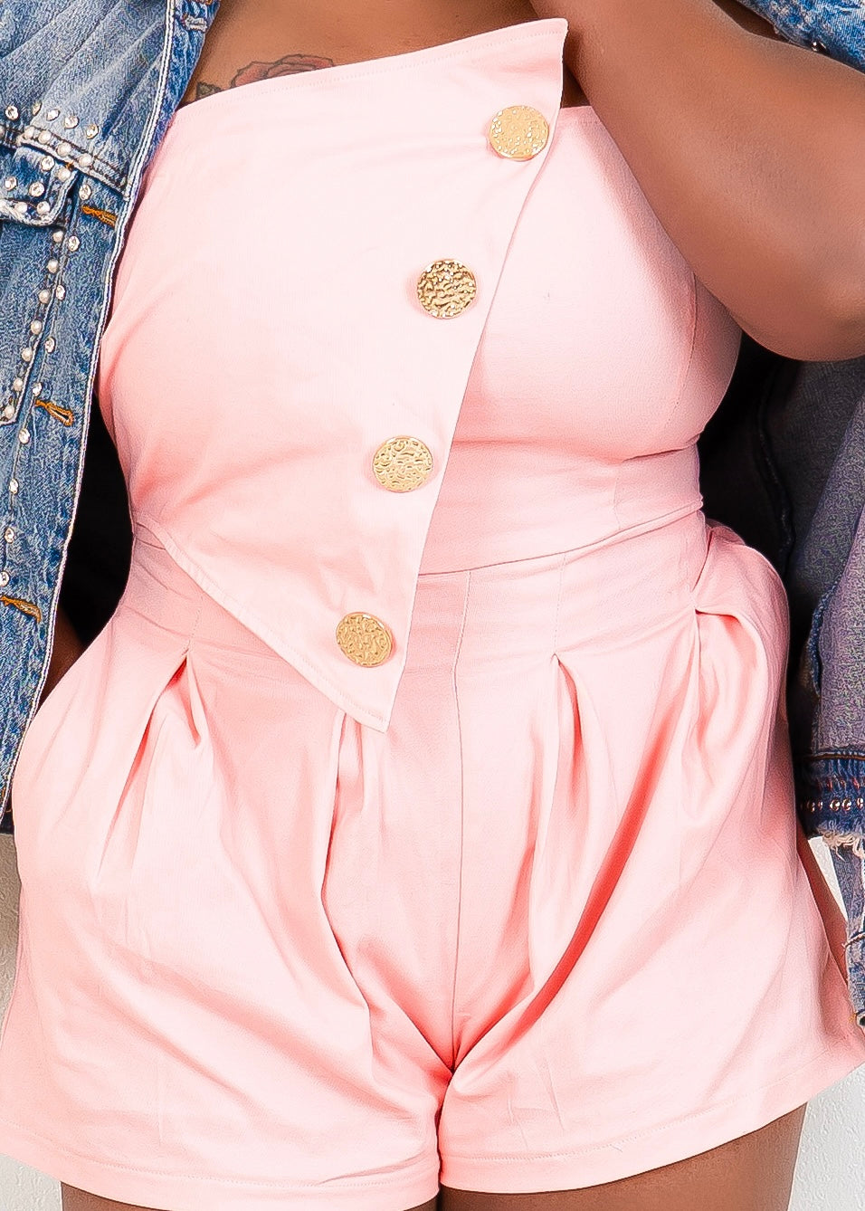 Close-up of peach pink strapless romper with pleated shorts and gold buttons