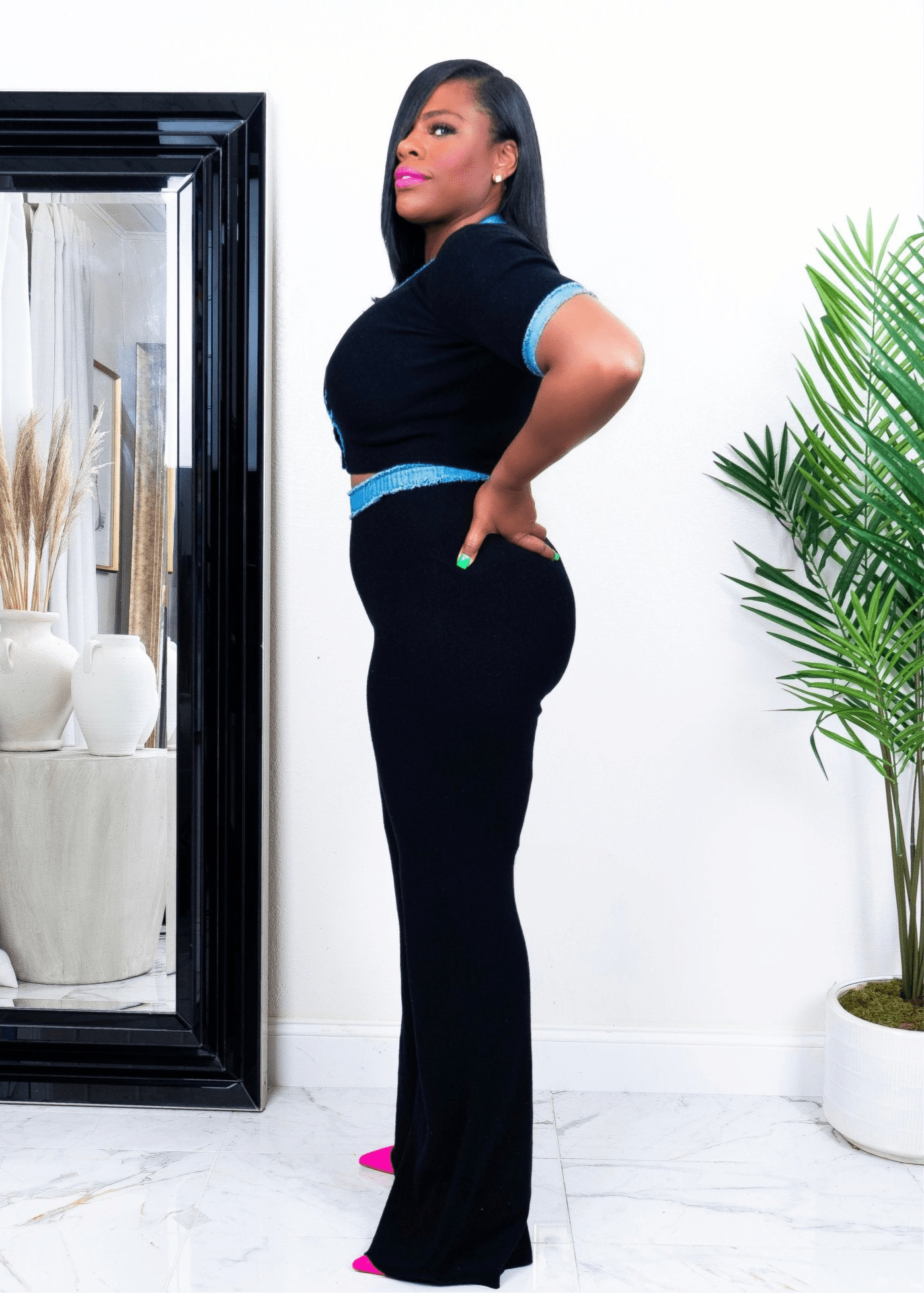 Side view of a woman wearing black wide-leg stretch pants and short sleeve V-neck top with blue trim – stylish two-piece  set from Opulent Gurlz California boutique
