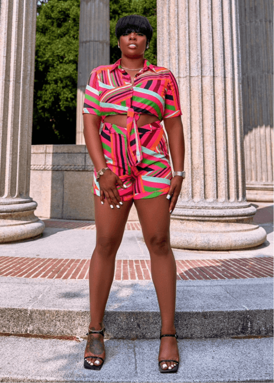 Model front view wearing a bold multicolor summer outfit with a button-up top and high-waisted shorts—vacation-ready style for confident, fashion-forward women.
