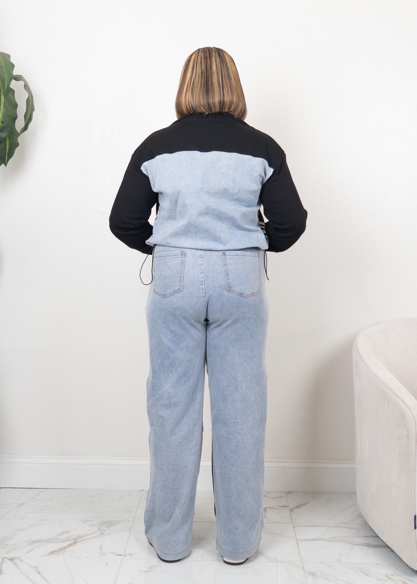 Back view of black contrast track set with cropped zip-up jacket, adjustable side drawstrings, and wide-leg denim panel pants