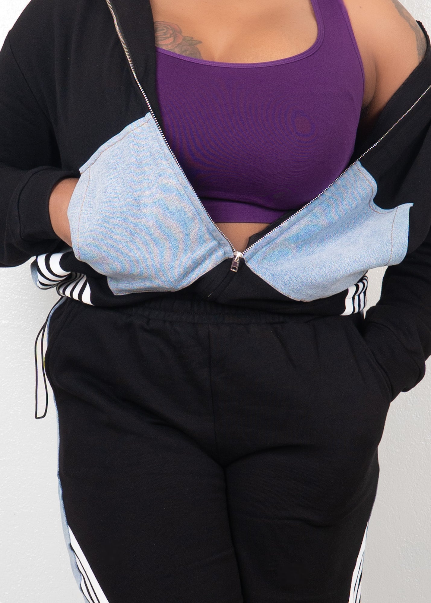 Close-up of black contrast track set featuring cropped zip-up jacket with denim panel pockets and adjustable zipper detail
