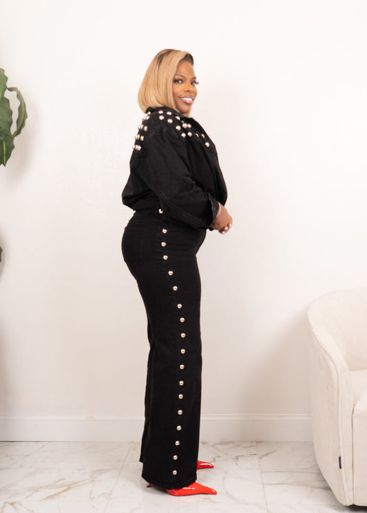 Side view of black studded denim set with rivet jacket and studded straight-leg jeans, styled with white tank and red heels