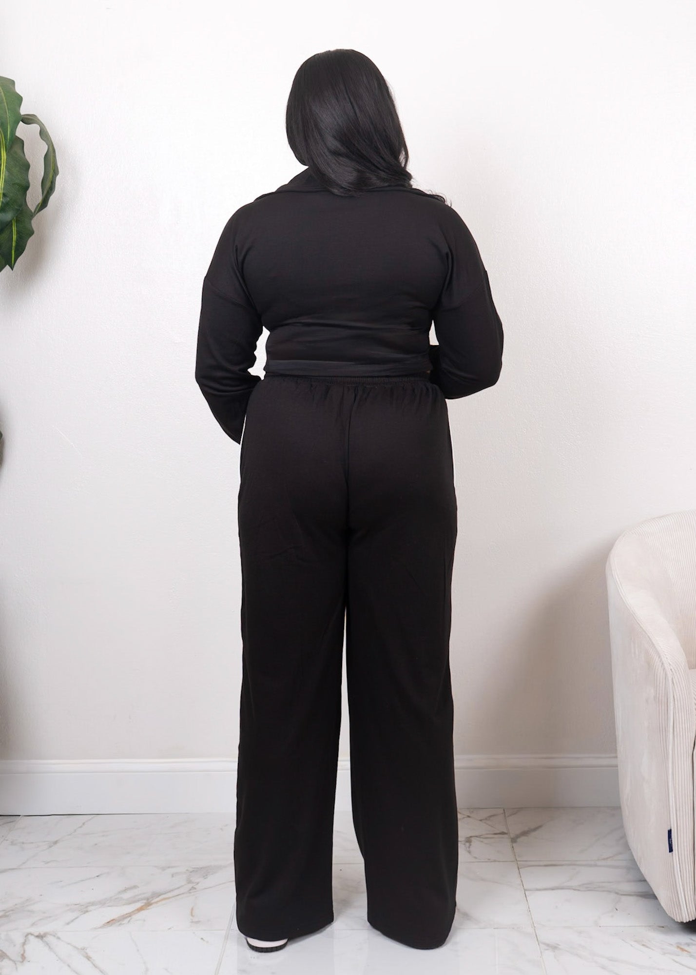 Black two-piece tracksuit with wide-leg pants and fitted zip-up jacket shown from the back for full coverage fit
