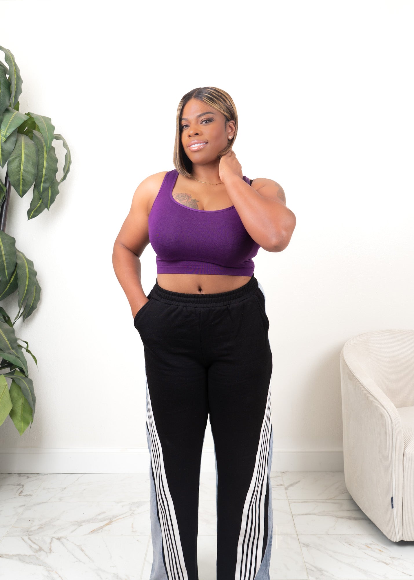 Black high-waisted wide-leg track pants with white stripe and denim panel detailing styled with a cropped tank top