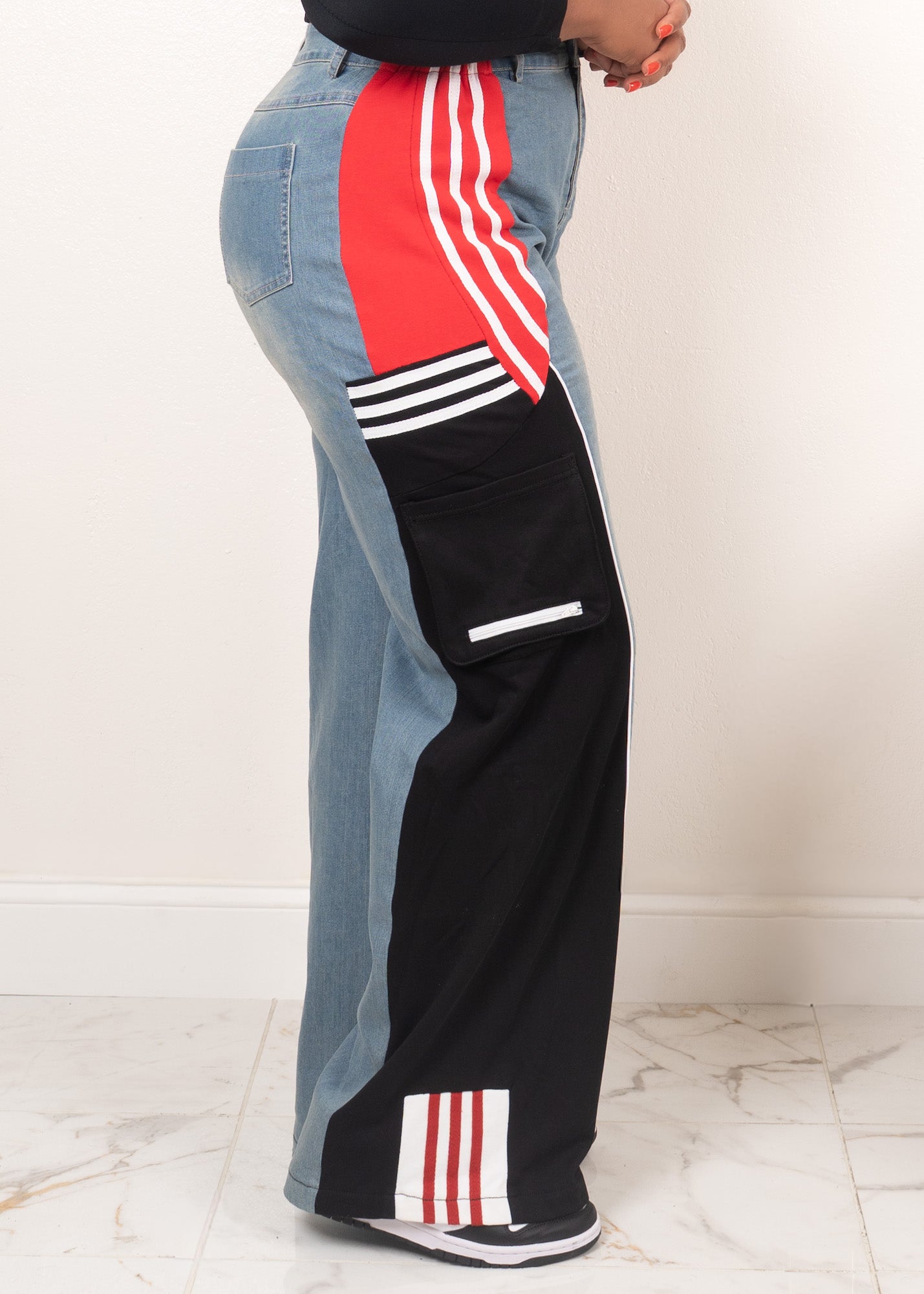 Black wide-leg track pants with denim contrast panels, red stripe detailing, and sporty colorblock design styled with sneakers