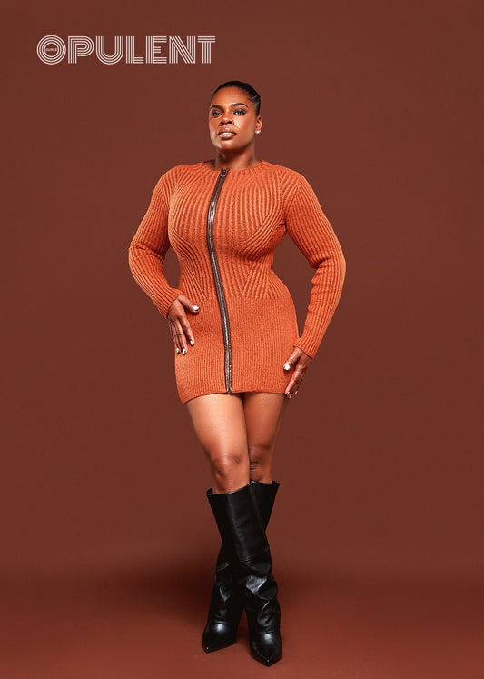 Woman wearing bold orange sweater dress with faux leather zipper front, ribbed knit texture, styled with black boots
