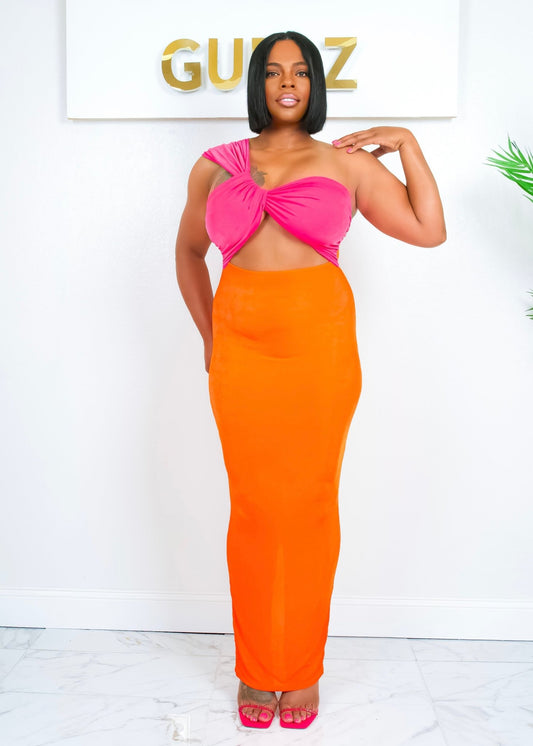 Model in front pose wearing the neon pink and orange Out Of Town Dress with one shoulder strap, standing confidently