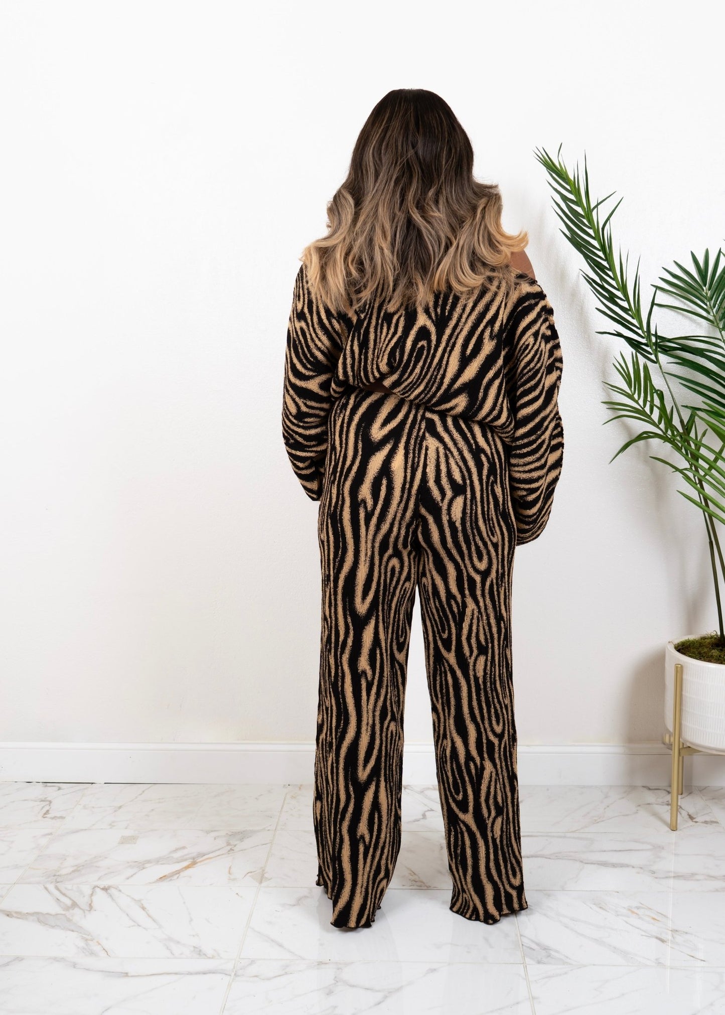 Model wearing The Wild Statement Set — two-piece abstract animal print knit with wide-leg pants and long-sleeve top, standing with back facing the camera